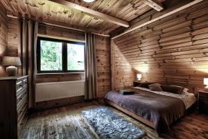 a bedroom with wooden walls and a bed and a window at Dom wakacyjny Chata Babci Wolf in Strzebowiska