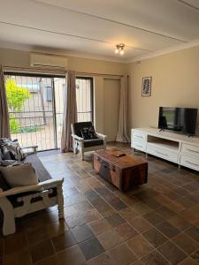 a living room with a tv and a couch and a coffee table at Cornerstone on Livingstone in Vryburg