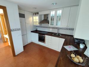a kitchen with white cabinets and a wooden floor at Casa any in Segovia
