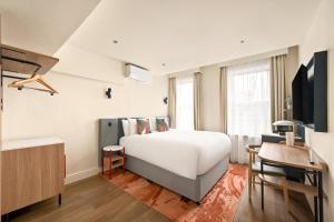 a bedroom with a large white bed and a desk at voco London - Bloomsbury by IHG in London