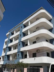 a tall white building with a blue sky in the background at Festim hotel in Durrës