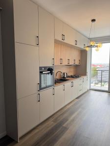 a kitchen with white cabinets and a large window at Nordic Star in Rădăuţi