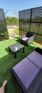 a person laying on the grass with a couch and a table at Le petit nid du Quercy in Anglars-Nozac