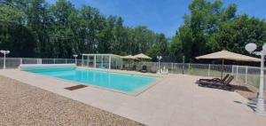 a swimming pool with chairs and umbrellas next to it at Les Mémis in Brantome en Perigord