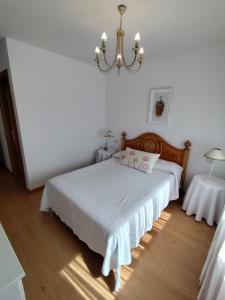 a white bedroom with a bed and a chandelier at Casa any in Segovia