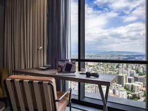 a room with a desk with a laptop and a window at Pullman Tbilisi Axis Towers in Tbilisi City