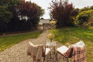a patio with two chairs and a table with a vase of flowers at Shepherd's Hut - Jasmine in Haverfordwest