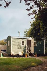 a green trailer with a table and chairs in a yard at Shepherd's Hut - Jasmine in Haverfordwest