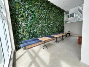 a green wall with tables and benches in a room at 1412 - Studio completo com varanda e vaga in São Paulo