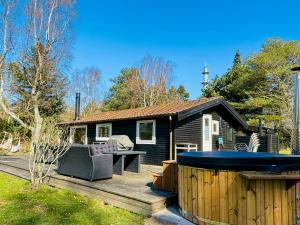 a house with a hot tub on a wooden deck at Summer House With Wilderness Bath By Kårup Forest in Fårevejle