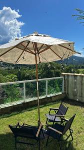 two chairs and an umbrella in the grass at Solar Paraty - Casa perto do centro com psicina in Paraty