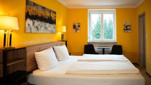 a bedroom with a bed with yellow walls and a window at Maiers Hotel in Bayerisch Eisenstein