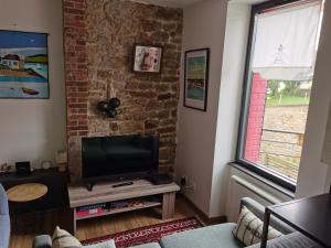 a living room with a tv and a brick wall at La maison Kerserho in Plouhinec