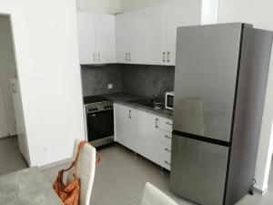 a kitchen with white cabinets and a stainless steel refrigerator at Arany-Lak Hajdúszoboszló in Hajdúszoboszló
