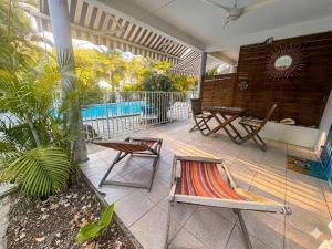 a patio with two chairs and a table and a pool at Studio accès piscine, plage à 50m in Le Gosier +10 photos