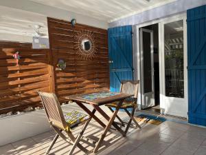 a table and chairs on a patio with a wooden wall at Studio accès piscine, plage à 50m in Le Gosier