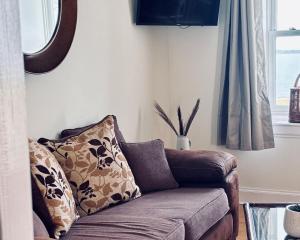 a brown couch with pillows in a living room at Bracken Cottage in Killean
