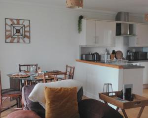 a living room with a table and a kitchen at Bracken Cottage in Killean