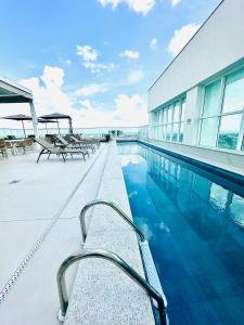 a swimming pool with tables and chairs next to a building at Ed Saint Moritz, Flat 02 com Garagem, SHN no Coração de Brasília in Brasília
