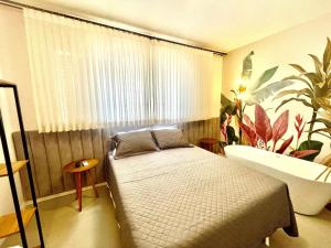 a bedroom with a bed and a bath tub at Incrível apto com banheira e garagem perto de tudo in Florianópolis