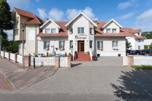 a white house with a fence in front of it at Bałtyk Resort in Rewal