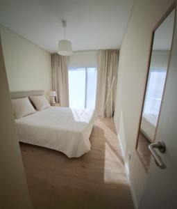 a bedroom with a white bed and a mirror at Garden House 2 in São Vicente Ferreira