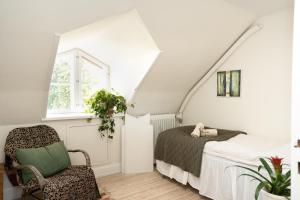a bedroom with a bed and a chair in a attic at Edelsminde Bed & Breakfast in Haslev