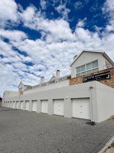 a long white building with four garage doors at Palm Springs in Struisbaai