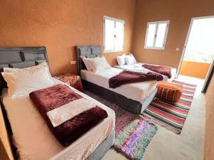 a bedroom with three beds in a room with windows at Pergolas Tamakouchte in Ouarzazate