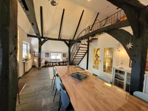 a dining room with a wooden table and a spiral staircase at Ferienhaus Heilhecker in Brake
