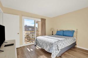 a bedroom with a bed with blue pillows and a window at Lighthouse Point Rental 8B in Tybee Island +43 photos