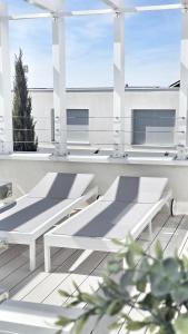 two white benches on a balcony with windows at Terra & Salt in Bibinje