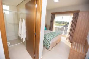 a bedroom with a bed and a bathroom with a window at Ilhas do Lago in Caldas Novas
