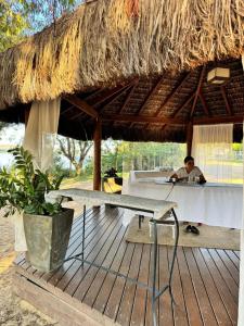 a man sitting at a table under a straw umbrella at Ilhas do Lago in Caldas Novas