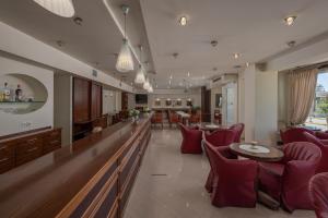 a restaurant with red chairs and tables and a bar at Filippos Hotel in Nea Moudania