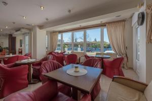 a restaurant with red chairs and tables and windows at Filippos Hotel in Nea Moudania