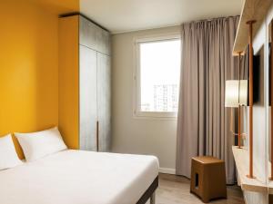 a hotel room with a bed and a window at IBIS BUDGET CAPAO Bonito in Capão Bonito