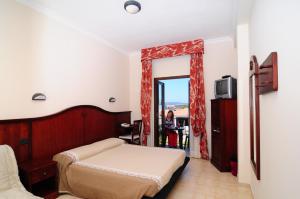 a bedroom with a bed and a woman sitting at a table at Hotel Stella Del Sud in Calasetta