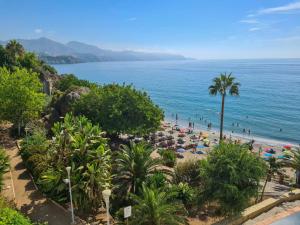 a beach with umbrellas and people in the water at Apartamentos Abril in Nerja