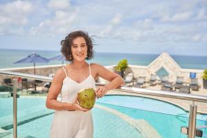 a woman holding a coconut in front of a swimming pool at Hotel Atlante Plaza in Recife