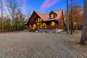 a large log home with a gambrel roof at Wide Glide Lodge - In-home Movie Room, Hot Tub and Large 1-acre property with Playset in Broken Bow
