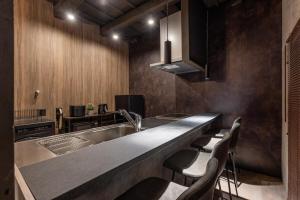 a kitchen with a sink and a counter with chairs at Betsuan Private Villa in Kuwana