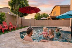 a man and a woman and a baby in a swimming pool at Pool Grill Games Chill - Surprise Awaits in Surprise