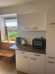 a kitchen with white cabinets and a microwave at Ute Urbaner in Irschen