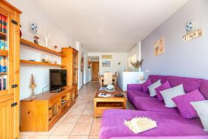 a living room with a purple couch and a tv at Apartamento Ca Na Fina, tranquilo y cerca de la playa de Es Pujols in Es Pujols