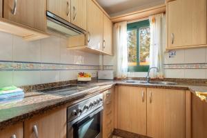 a kitchen with wooden cabinets and a sink and a stove at Apartamento Ca Na Fina, tranquilo y cerca de la playa de Es Pujols in Es Pujols +15 photos