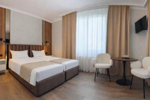 a hotel room with a bed and a table and chairs at Pensiunea Brici in Cluj-Napoca