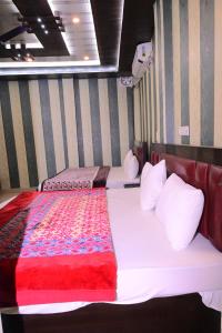 two beds in a room with a red and white blanket at Swastik homestay ayodhya in Ayodhya