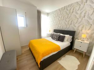 a bedroom with a bed with a yellow blanket at Apartamento A pie de Playa in Miño +4 photos