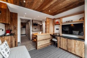 a kitchen with wooden cabinets and a counter in a room at Alliey & Spa Piscine Appart-hôtel Serre chevalier in Le Monêtier-les-Bains